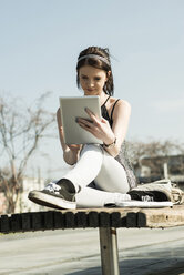 Junge Frau mit Tablet-Computer sitzt auf einer Bank - UUF000062