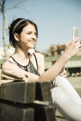 Portrait of young woman with coffee to go using smartphone - UUF000136