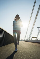 Junge Joggerin in Bewegung auf einer Brücke - UUF000094