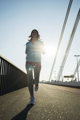 Young female jogger on the move on a bridge - UUF000094
