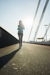 Young female jogger on the move on a bridge - UUF000157