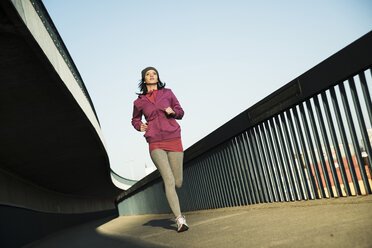 Young female jogger on the move on a bridge - UUF000102