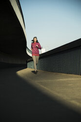 Young female jogger on the move on a bridge - UUF000103