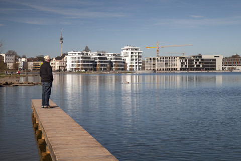 Deutschland, Nordrhein-Westfalen, Dortmund-Hoerde, Phoenix-See, Seniorin auf Holzsteg stehend, lizenzfreies Stockfoto