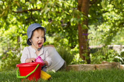 Toddler playing with sandbox toy in the garden - LVF000990