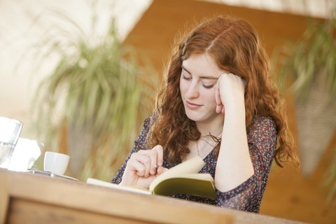 Junge Frau mit Notizbuch schreibt in einem Café, lizenzfreies Stockfoto