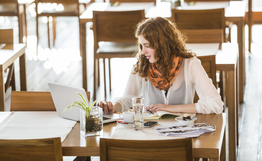 Junge Frau benutzt ein Notebook in einem Café - DISF000722