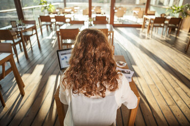 Junge Frau benutzt ein Notebook in einem Café - DISF000708