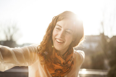 Portrait of smiling young woman standing in backlight - DISF000715