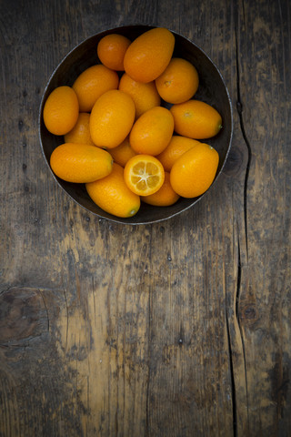 Bowl of kumquats on wooden table stock photo