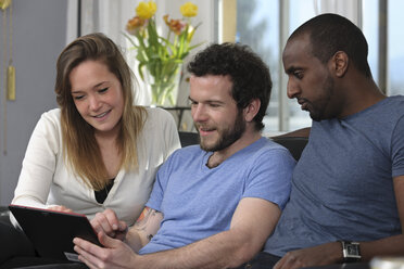 Drei Freunde benutzen einen Tablet-Computer zu Hause - LAF000716