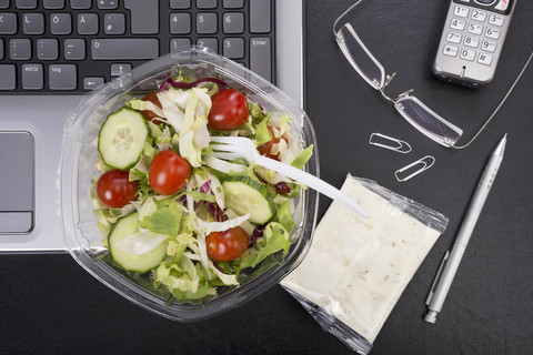 Workplace with mixed salad on laptop stock photo
