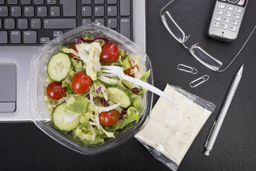 Workplace with mixed salad on laptop - CSTF000216