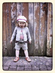 Germany, Hassia, Hofheim, Little girl in Bavarian Leather Trousers in front on grunge wooden wall - IPF000100