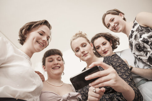 Young women in vintage dresses looking at cell phone - DISF000760