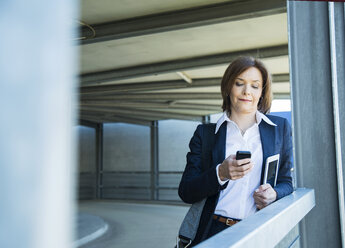 Porträt einer Geschäftsfrau, die eine SMS liest - UUF000106