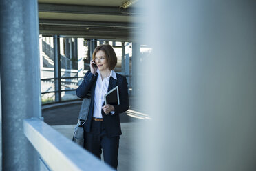 Business woman telephoning with smartphone on parking level - UUF000110