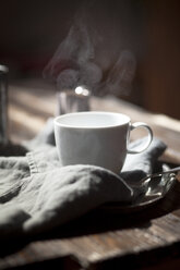 Cup of steaming tea on silver plate and wooden table - SBDF000763