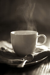 Dampfender Tee in weißer Teetasse auf Holztisch - SBDF000765
