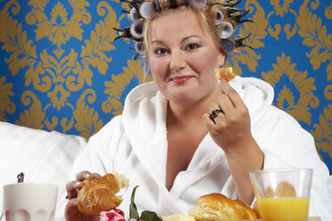 Porträt einer Frau mit Lockenwicklern und weißem Bademantel beim Frühstück im Bett - CSBF000008