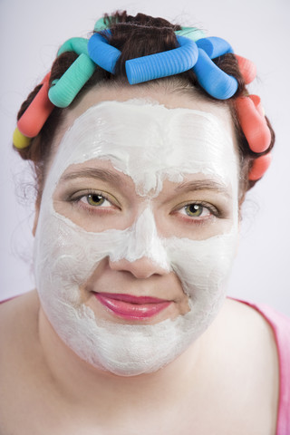 Porträt einer Frau mit Schönheitsmaske und Lockenwicklern, lizenzfreies Stockfoto