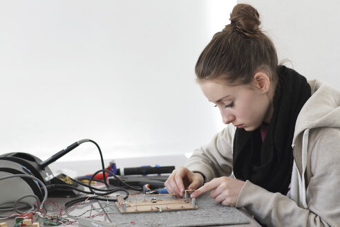 Junge Frau bei der Arbeit an einem optischen Sensor in einer Elektronikwerkstatt - SGF000536