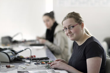 Two young women working on optical sensor in an electronic workshop - SGF000537