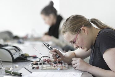 Two young women working on optical sensor in an electronic workshop - SGF000542