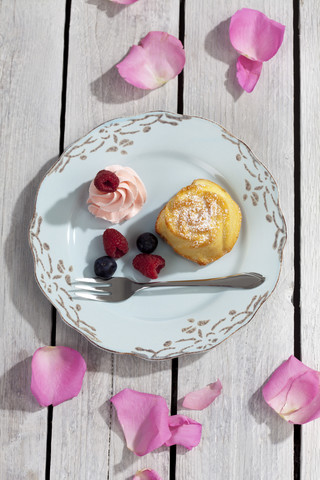 Muffin, Beeren und Sahne auf Teller und Holztisch, Blick von oben, lizenzfreies Stockfoto