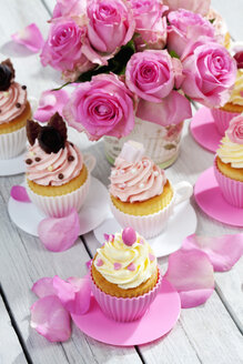 Cupcakes und Blumenvase mit rosa Rosen auf Holztisch - CSF021212