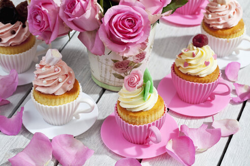 Cupcakes und Blumenvase mit rosa Rosen auf Holztisch - CSF021213