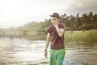 Bekleideter junger Mann im Baggersee stehend - MUMF000002