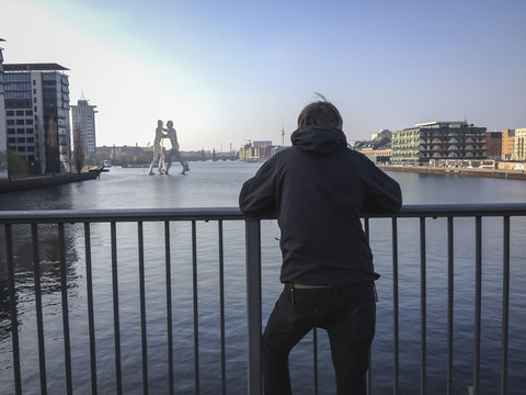 Deutschland, Berlin, Elsenbrücke, junger Mann schaut auf Spree mit Maulwurfsmann, lizenzfreies Stockfoto