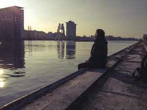 Deutschland, Berlin, Treptow, junger Mann sitzt bei Sonnenuntergang auf der Seebrücke - FBF000340