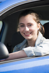 Lächelndes jugendliches Mädchen im Auto sitzend, Teilansicht - UUF000176