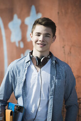 Portrait of smiling teenager with headphones and folders - UUF000188