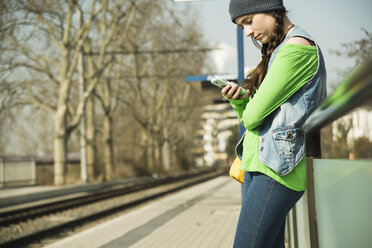Teenage girl using smartphone at platform - UUF000194