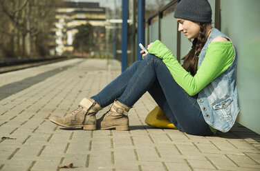 Teenage girl using smartphone at platform - UUF000195