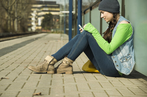 Teenager-Mädchen benutzt Smartphone am Bahnsteig - UUF000195