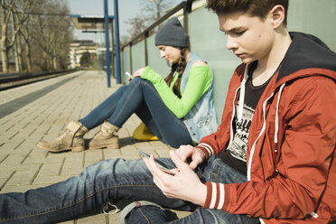 Teenager und junges Mädchen warten auf dem Bahnsteig - UUF000199