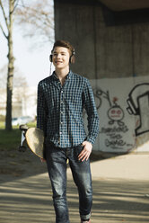 Teenager with skateboard hearing music - UUF000168