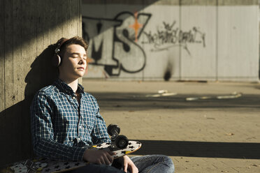 Teenager with skateboard hearing music - UUF000169