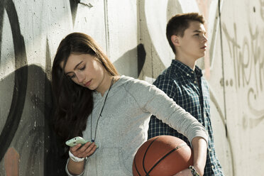 Teenagerpaar mit Basketball und Smartphone - UUF000171