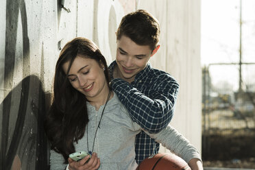 Teenagerpaar mit Basketball und Smartphone - UUF000172