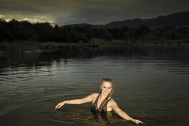 Young woman bathing with evening dress in lake at dawn - FCF000015
