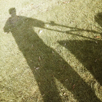 Germany, North Rhine-Westphalia, Petershagen, Shadow of a man with a lawn mower. - HAWF000083