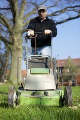 Germany, Petershagen, Man mowing lawn - HAWF000093