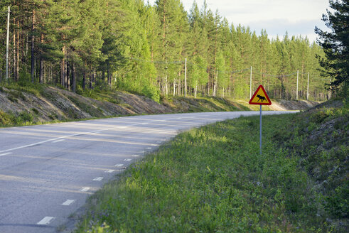 Schweden, Jokkmokk, Elch überquert Straßenschild an Landstraße - BR000416