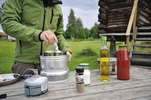 Schweden, Leksand, Mann kocht Nudeln auf Campingkocher - BR000312