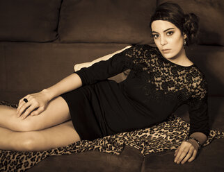 Porträt einer jungen Frau mit kleinem schwarzen Kleid auf einer Couch liegend - FCF000004